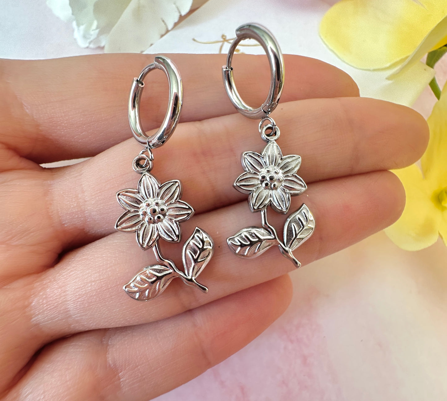 Silver flower drop hoop earrings.