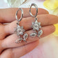 Silver flower drop hoop earrings.