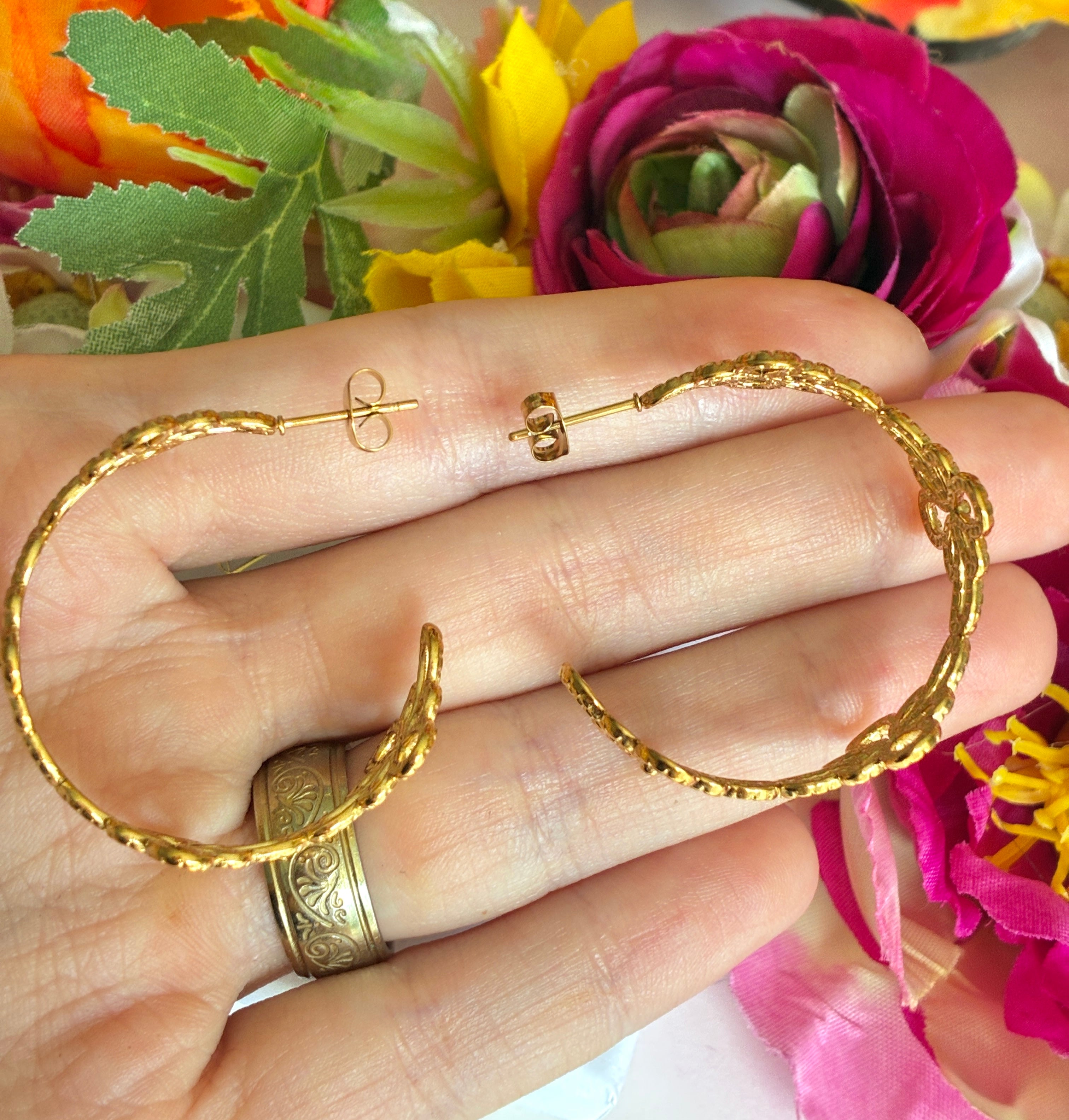 Gold floral pattern hoop earrings.