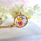 Gold real flower capsule locket necklace.