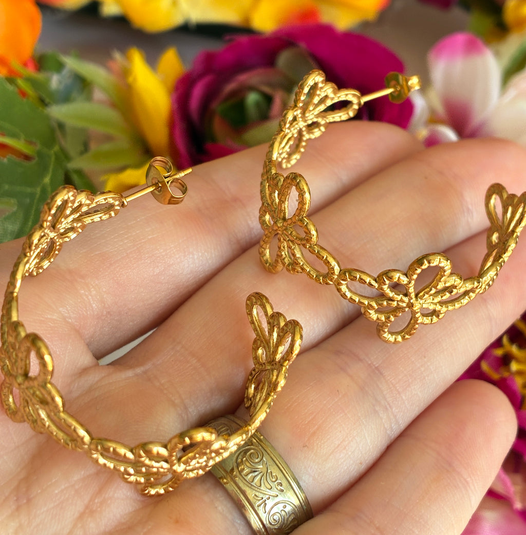 Gold floral pattern hoop earrings.