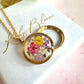 Gold real flower capsule locket necklace.