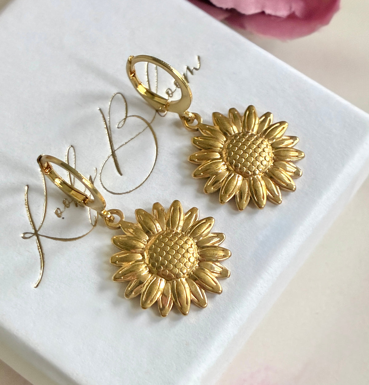 Gold sunflower huggie earrings.