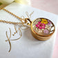 Gold real flower capsule locket necklace.