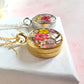 Gold real flower capsule locket necklace.