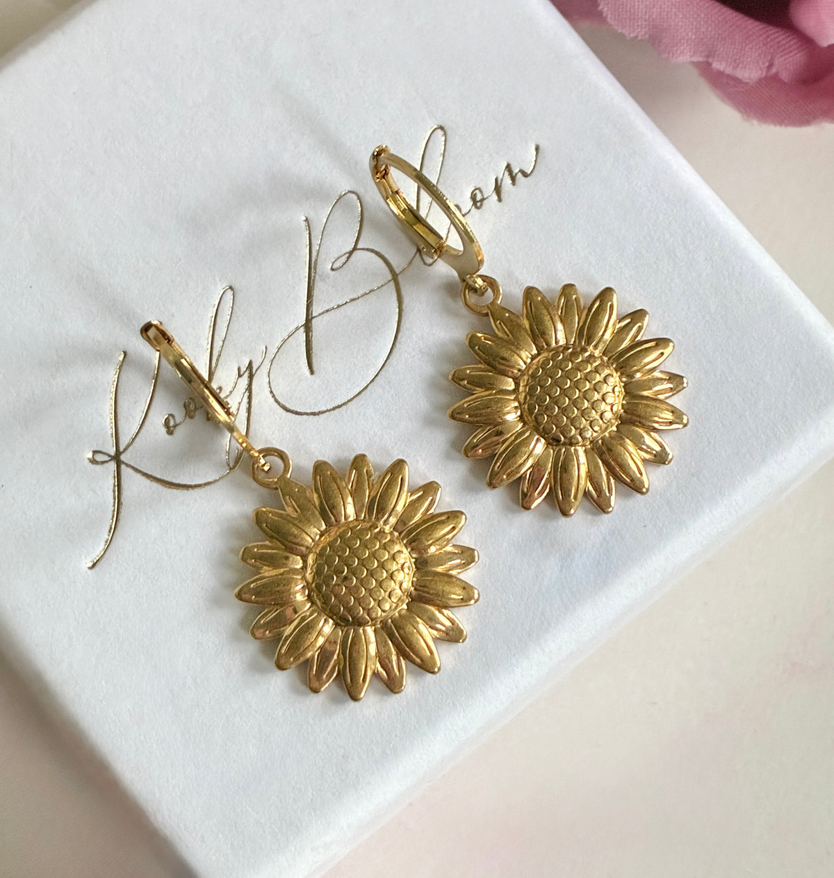 Gold sunflower huggie earrings.