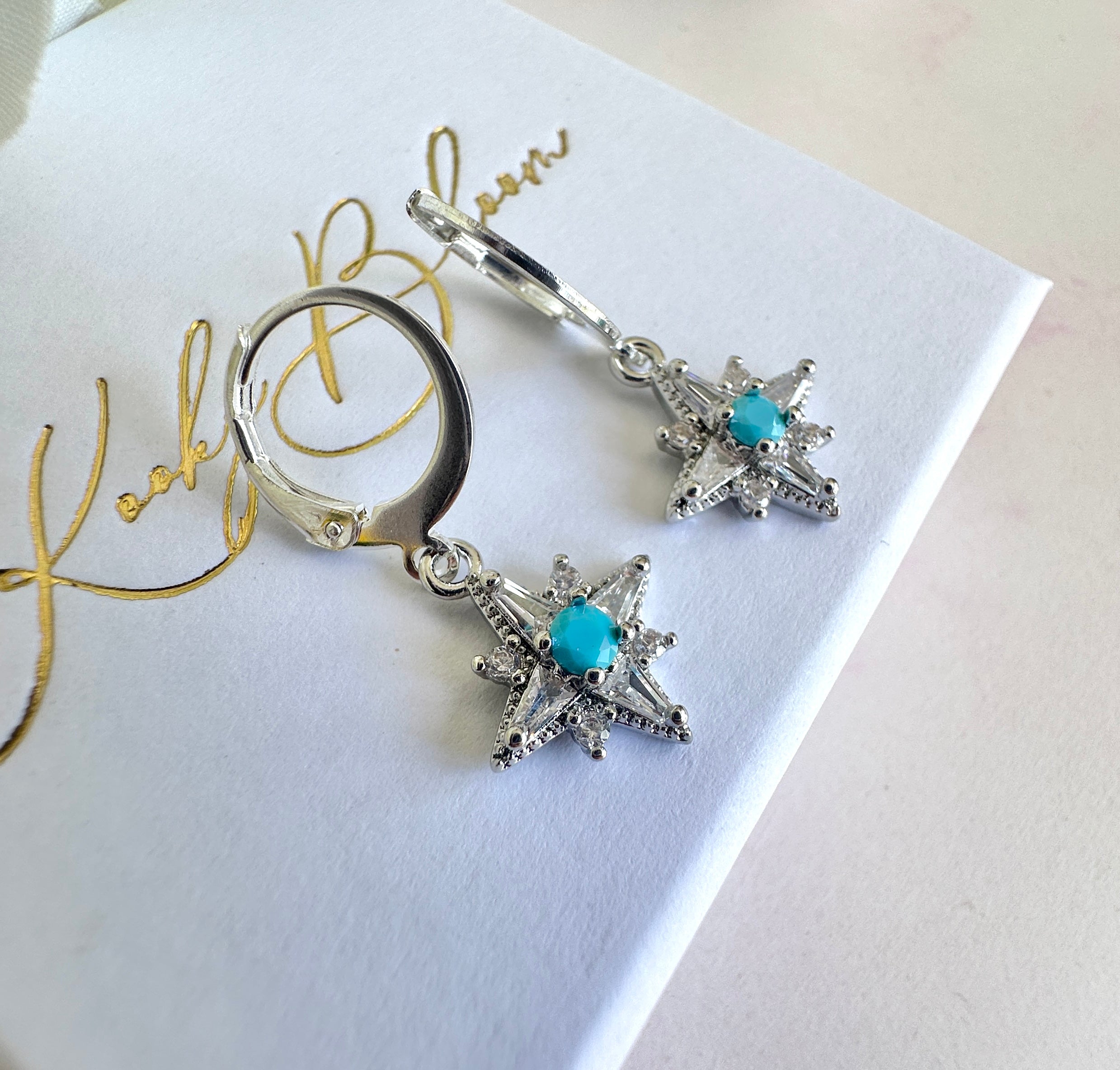 Silver tiny Cz Blue stone Star huggie earrings.