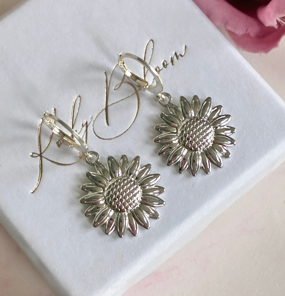 Silver Sunflower huggie earrings.